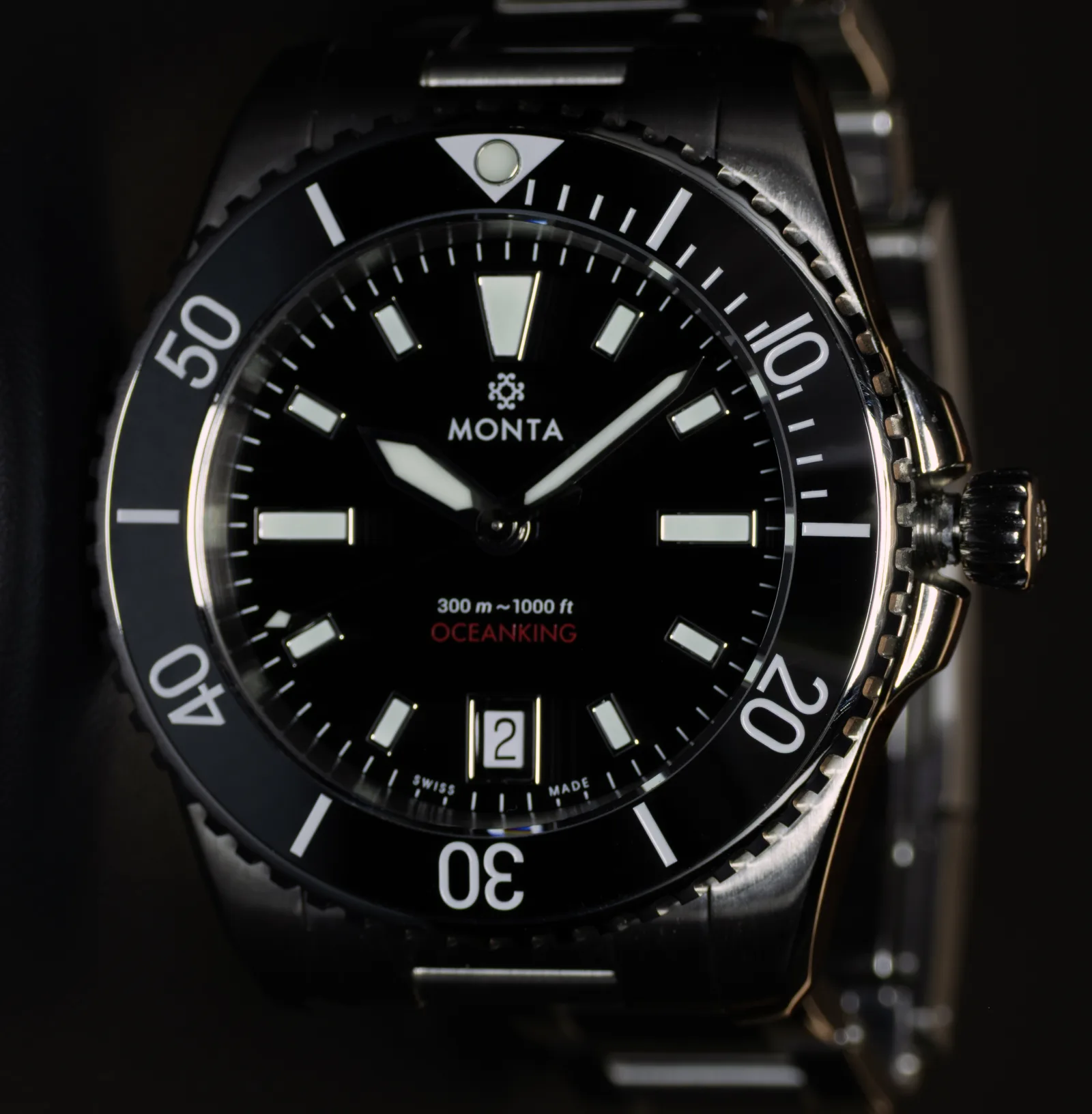 The Oceanking's black dial straight on: applied lumed markers, date window at six, red model name, and the ceramic bezel's lumed pip at twelve.
