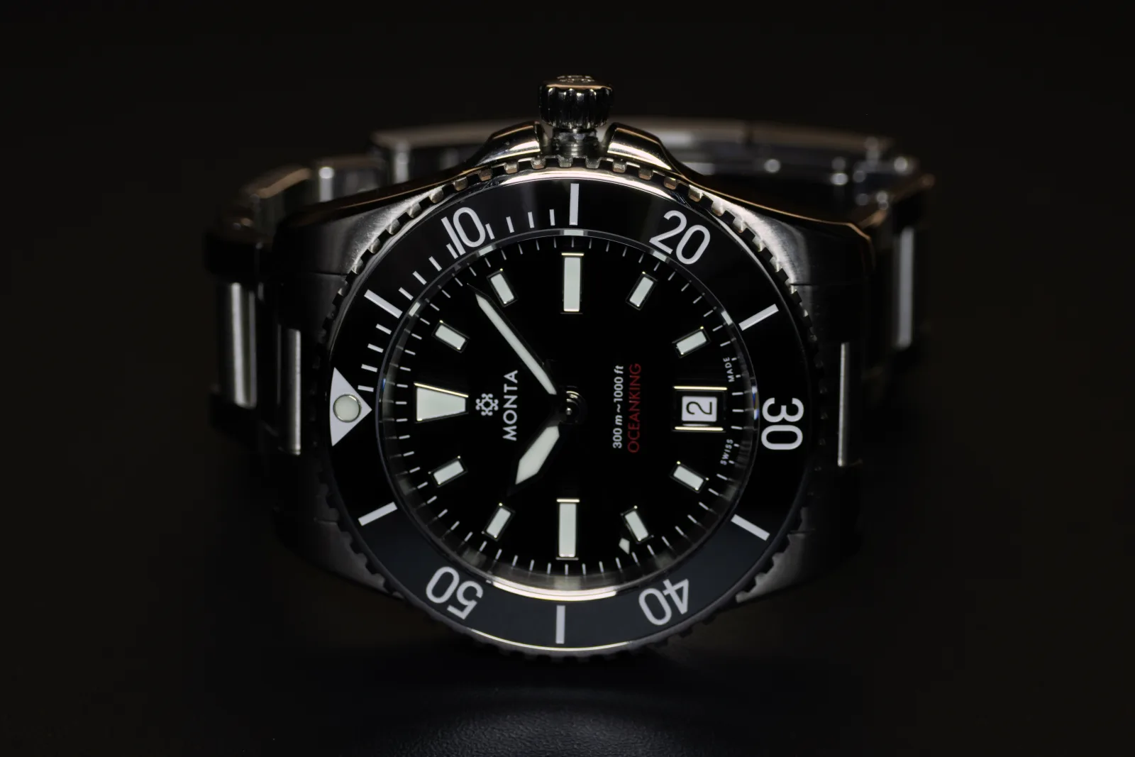 MONTA Oceanking with a black dial and black ceramic bezel on its steel bracelet, seen at an angle against black.