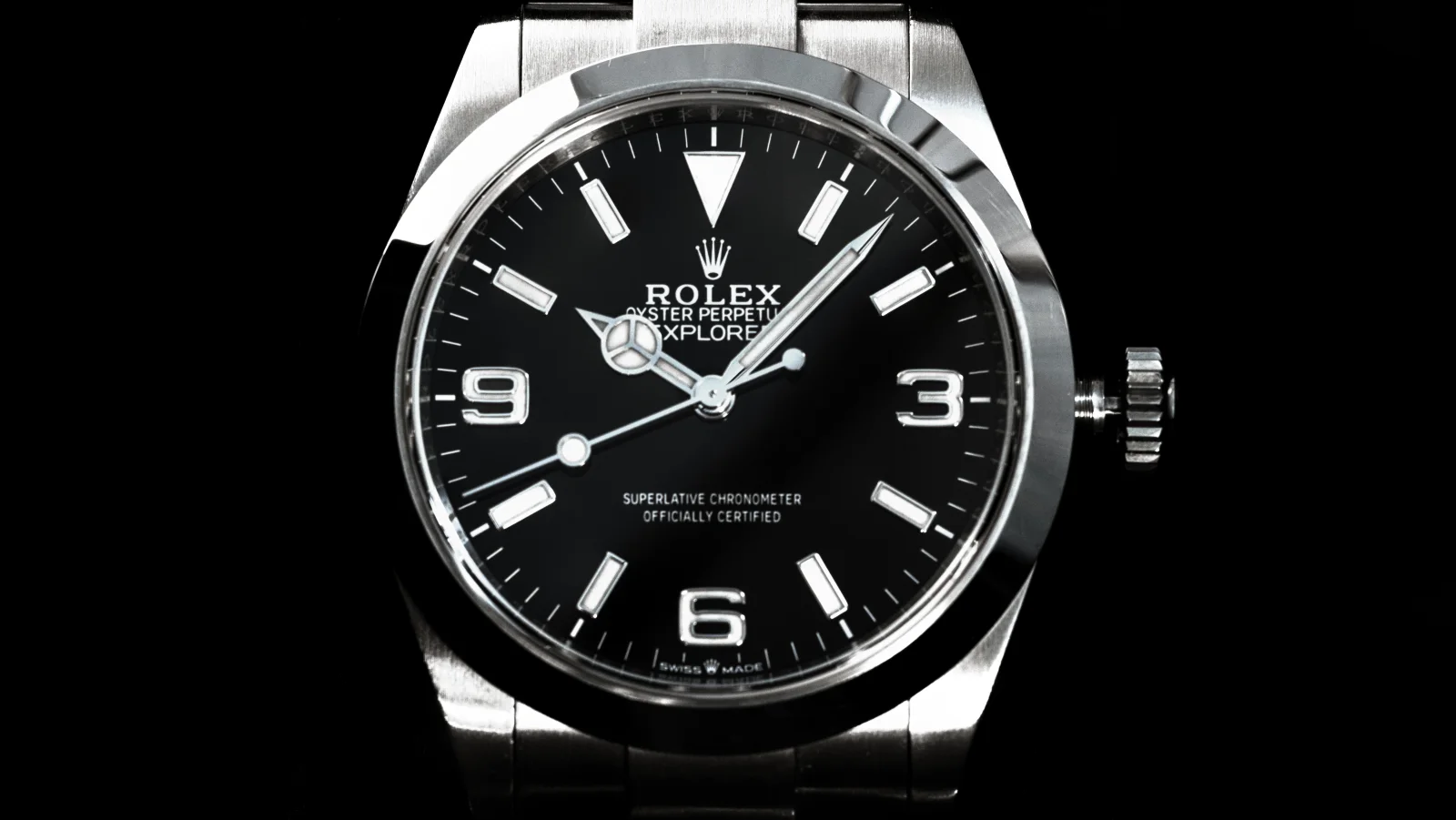 The Explorer dial straight on: black, with 3, 6 and 9 numerals, a triangle at twelve, baton markers, and Superlative Chronometer, Officially Certified and Swiss Made printed on it.